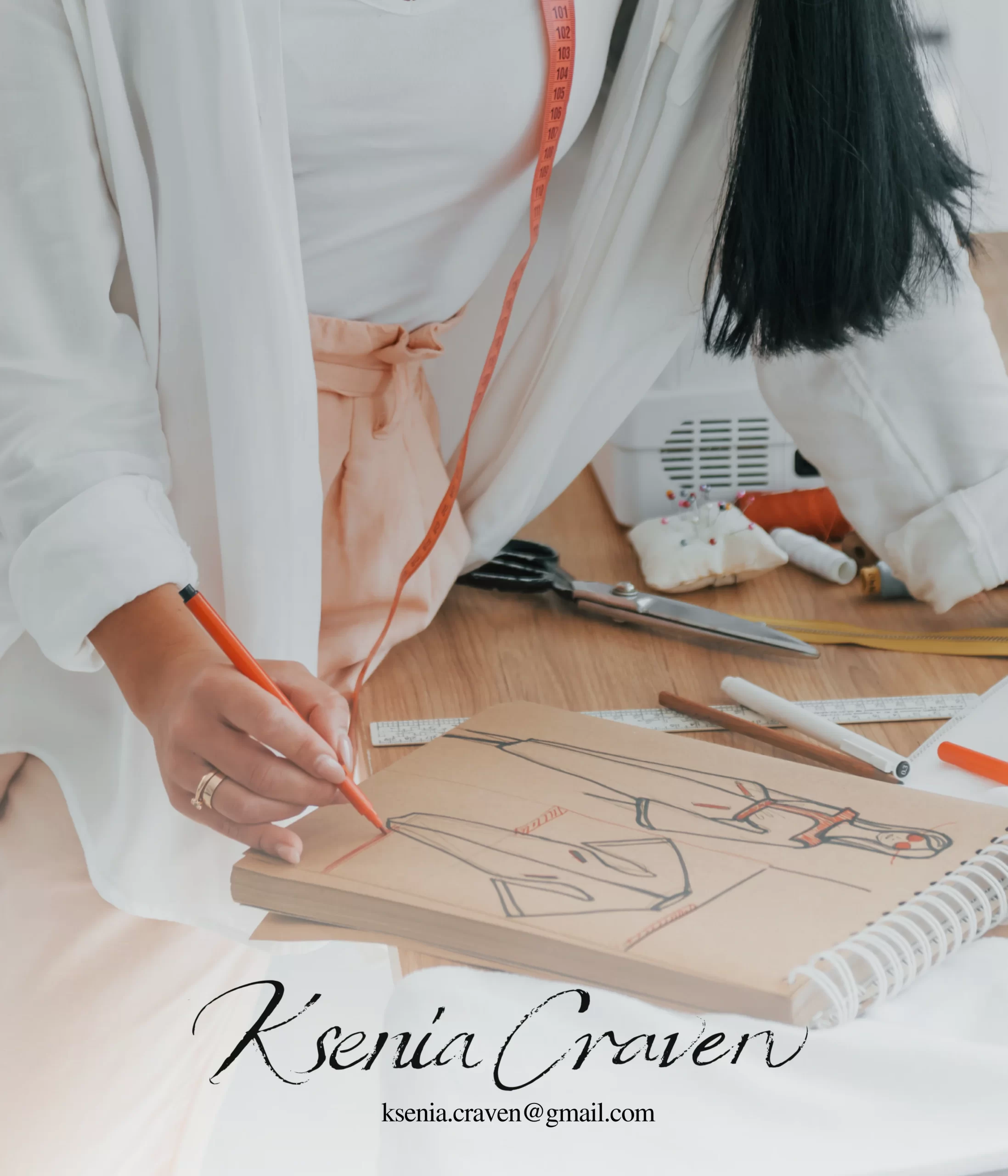 Fashion designer sketching a garment on brown paper with a red marker among sewing tools and measuring tape.