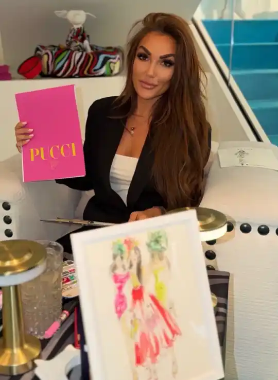 Ksenia Craven holding a pink Pucci book with fashion illustrations and a luxury studio background.