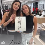 Two women in a retail store holding a custom hand-drawn fashion illustration by Ksenia Craven.