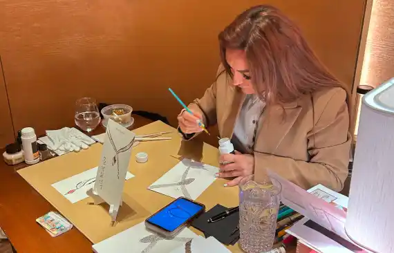 Illustrator Ksenia Craven hand-painting fine jewelry sketches and luxury designs at a live brand activation.
