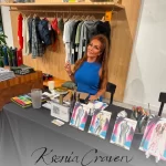 Fashion illustrator Ksenia Craven at a live sketching event with watercolor paintings and art supplies.