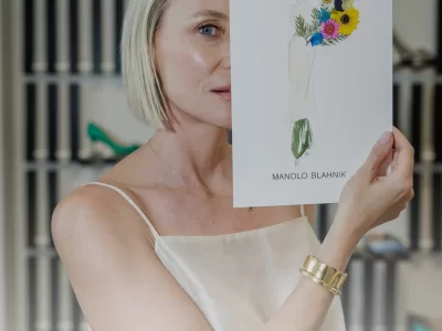 A woman holding a custom botanical fashion illustration created by Ksenia Craven for a Manolo Blahnik campaign.